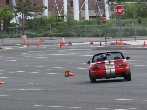 2001 Mercury Grand Marquis - A red convertible sports car navigates a cone course, with a 'SUPERMOTORS.NET' watermark at the bottom.