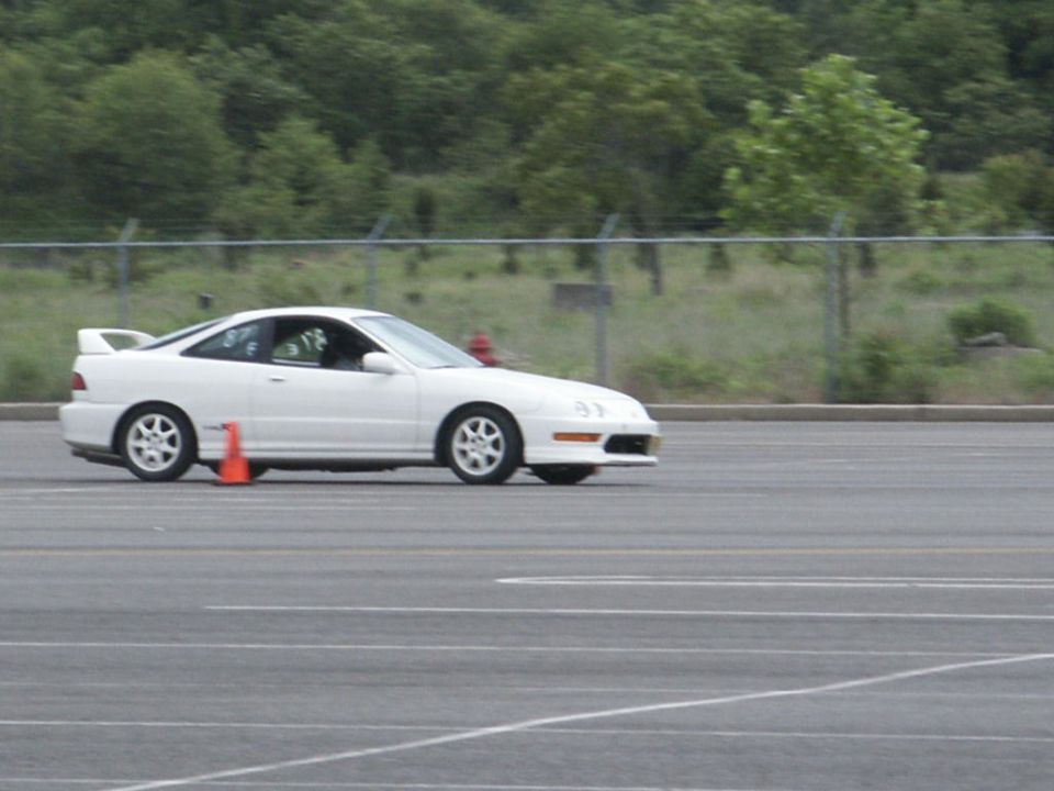 White Acura Integra coupe on a track with orange cones, side view