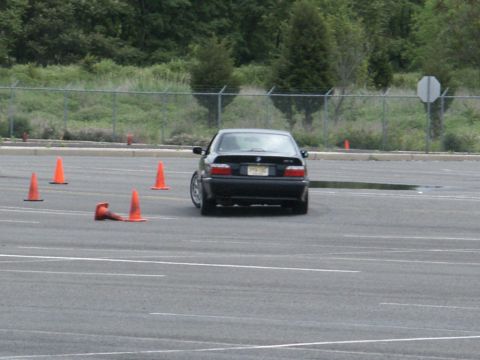 2001 Mercury Grand Marquis - A black BMW sedan navigates a course marked by orange cones on a wet asphalt lot.