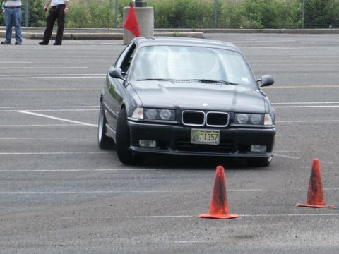 2001 Mercury Grand Marquis - A dark BMW E36 sedan is shown from the front, maneuvering through a course with orange cones.