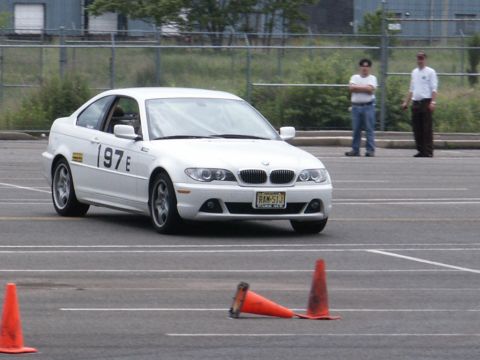 2001 Mercury Grand Marquis - A white BMW 3 series coupe navigates a course marked by traffic cones, with two spectators in the background.