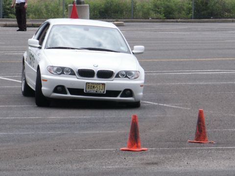 2001 Mercury Grand Marquis - A white 2001 BMW 3 series sedan is seen from the front, maneuvering through an obstacle course marked by traffic cones.