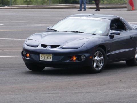 2001 Mercury Grand Marquis - A dark blue Pontiac Firebird is shown from the front in this photo.