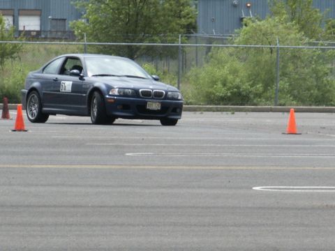 2001 Mercury Grand Marquis - A blue BMW M3 navigates a course marked by orange cones on a paved lot.