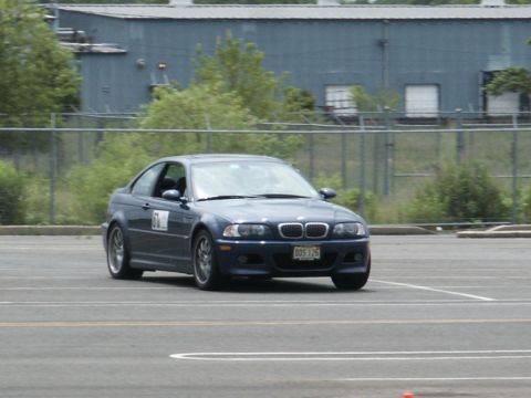2001 Mercury Grand Marquis - A blue coupe, possibly a BMW M3, navigates a turn on a race track with a building in the background.