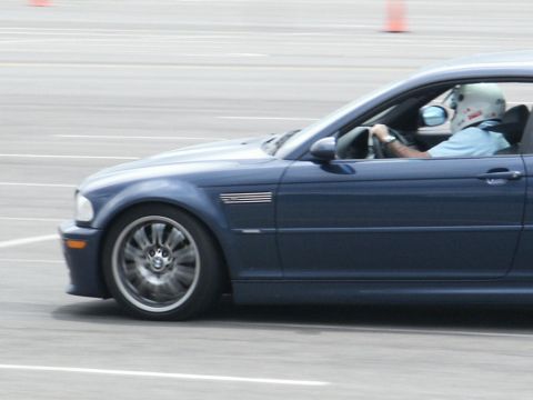 2001 Mercury Grand Marquis - Driver in a helmet navigates a blue BMW M3 during a track event.