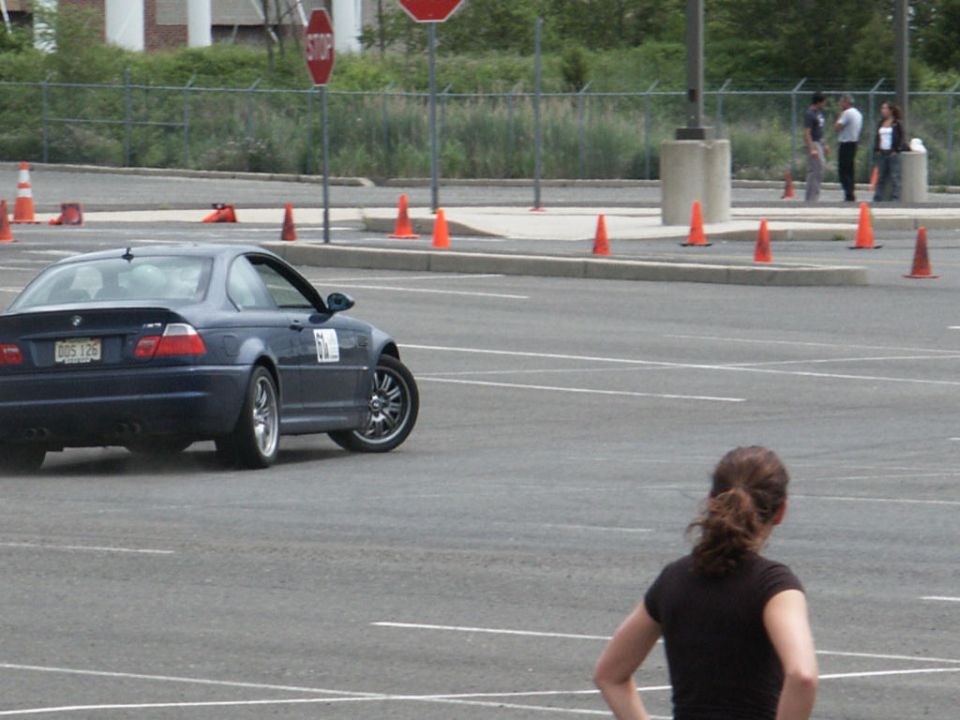 Dark blue BMW M3 coupe with racing numbers on the door, seen from rear-left