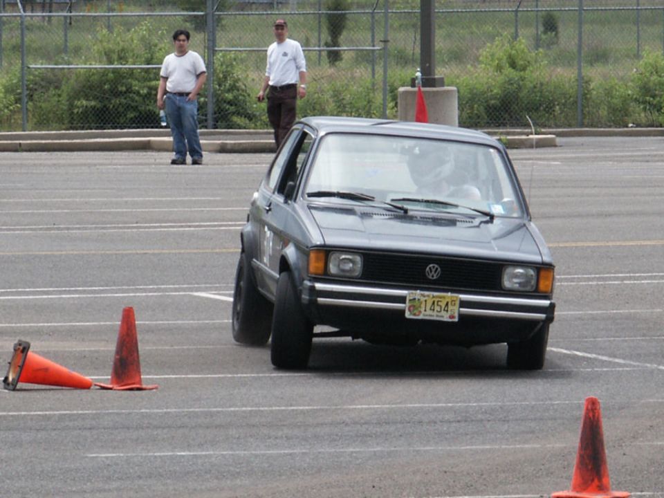 Gray Volkswagen Golf GTI doing an autocross course, navigating around orange cones