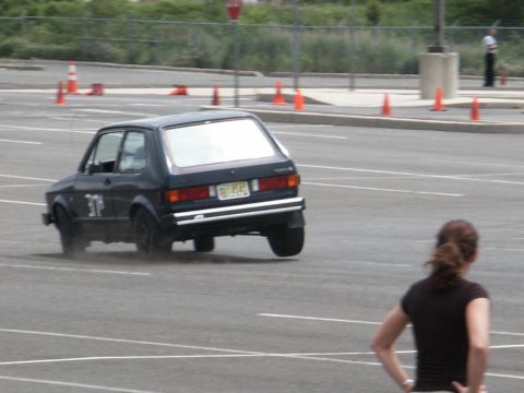 2001 Mercury Grand Marquis - A dark Volkswagen Golf Mk1 is seen from the rear during a driving event in a parking lot.
