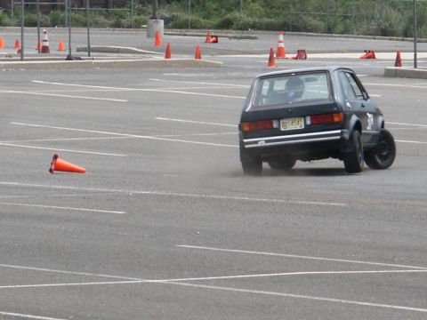 2001 Mercury Grand Marquis - A dark hatchback navigates an autocross course marked by orange cones in a parking lot.