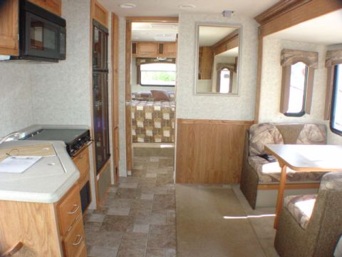 2005 Chevrolet C-6500/Kodiak - Interior view of an RV, including the kitchen, bedroom entrance, and a dinette area.
