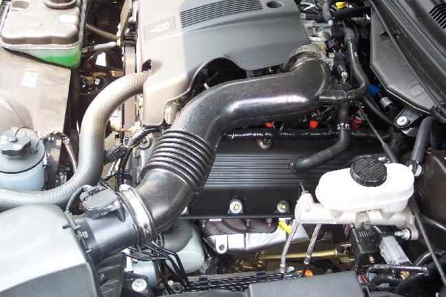 Engine bay close-up showing intake duct, valve cover and brake master cylinder reservoir