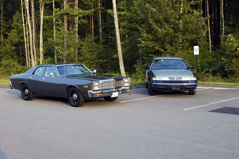 Grey 1970s Dodge sedan with steel wheels and dog-dish caps parked in a lot