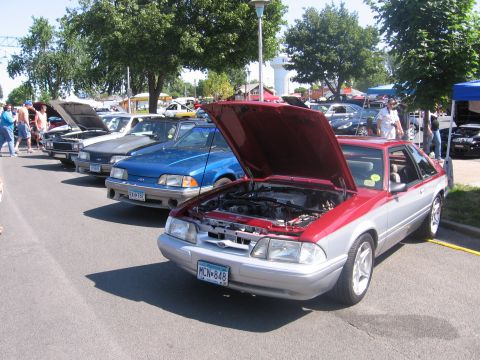 1989 Ford Mustang - Several cars are lined up with their hoods open at an outdoor event.