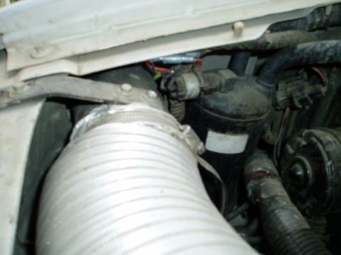 2000 Ford E350 - Tight engine-bay shot of a silver flexible corrugated intake duct routed up through the inner fender toward the cowl, part of a snorkel-sty…