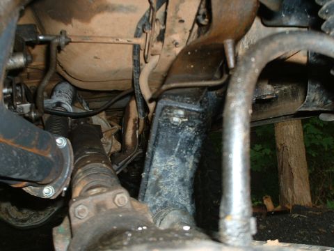1985 Ford Bronco - Underside view of a truck chassis showing the driveshaft and U-joint yoke running back to the transmission, with the boxed frame rail, cros…