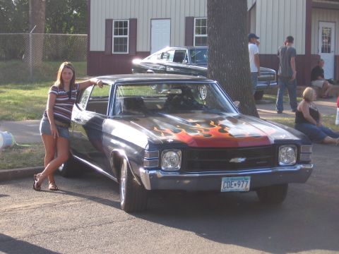 1989 Ford Mustang - A 1970 Chevrolet Chevelle is shown with custom flame graphics on the hood, parked next to a woman.