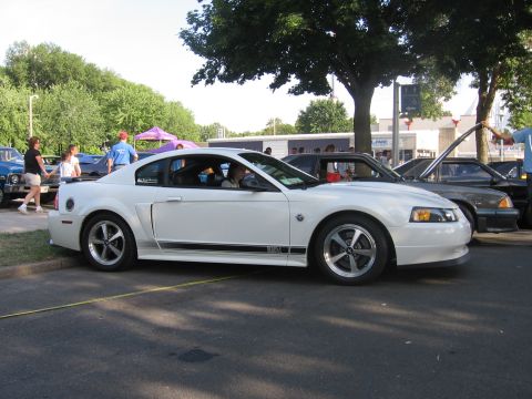 1989 Ford Mustang - White Ford Mustang with black stripe on the side, parked at an outdoor event.