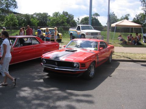 1989 Ford Mustang - A red 1970 Ford Mustang Boss 302 is parked at an outdoor car show.