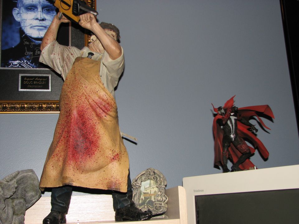 Leatherface action figure holding a chainsaw, with a framed picture of Pinhead behind it. Spawn figure on right