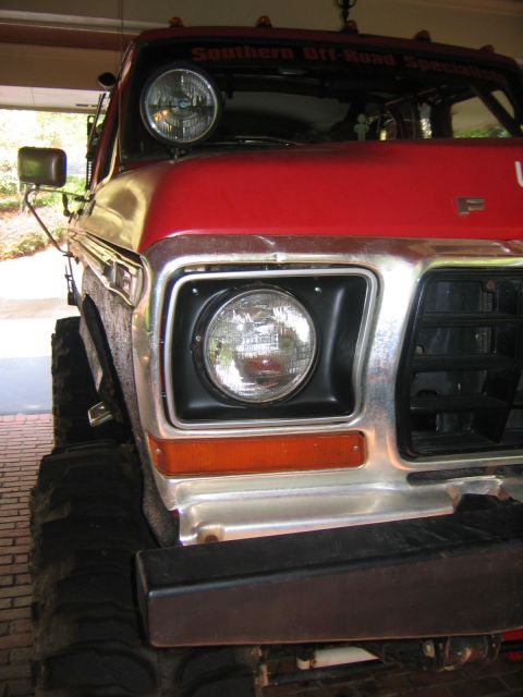 1979 Ford Bronco - Front view of a red 1979 Ford Bronco, modified with large tires and auxiliary lighting.