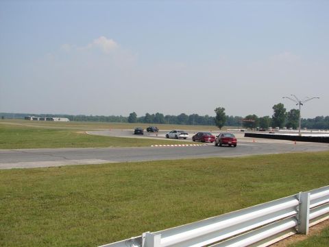 1992 Ford Taurus - Cars navigate a race track with green grass and trees in the background.