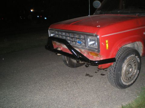 1985 Ford Bronco II - The front of a red Ford pickup truck is shown at night, equipped with a black bull bar.
