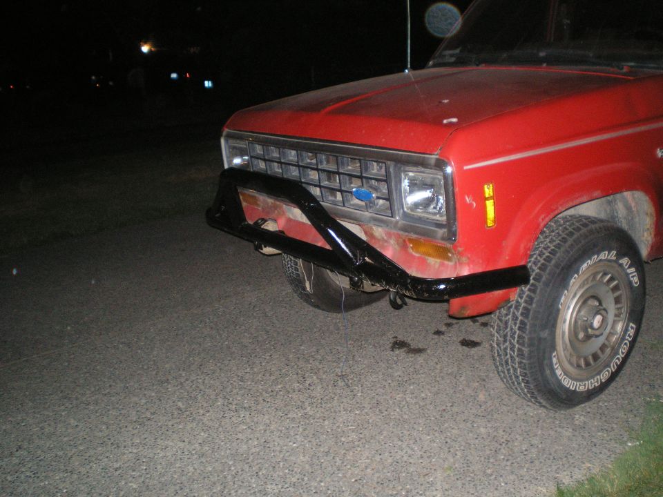front end of a red Ford pickup truck with a black bull bar and a blue Ford emblem on the grille