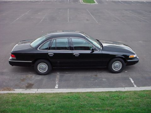 1998 Ford Crown Victoria - A black 1998 Ford Crown Victoria sedan is shown from the side in an empty parking lot.