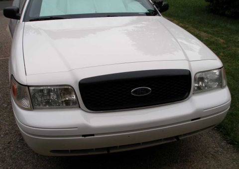 2001 Ford Crown Victoria - The front of a white 2001 Ford Crown Victoria is shown, a black grille and clear headlights.