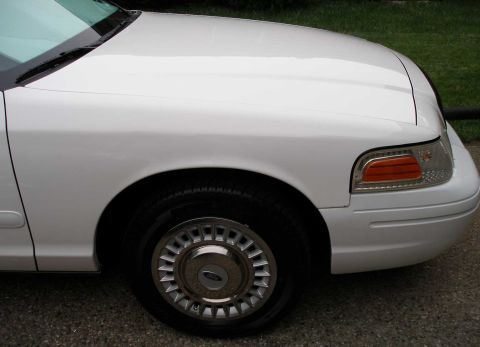 2001 Ford Crown Victoria - Front passenger side view of a white 2001 Ford Crown Victoria, showing the fender and wheel.