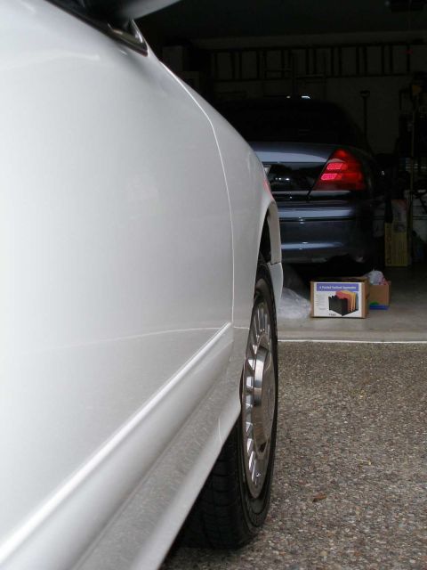 2001 Ford Crown Victoria - A white car's side profile is shown, with a dark sedan parked behind it in a garage.