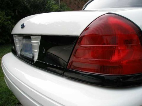 2001 Ford Crown Victoria - The rear of a white 2001 Ford Crown Victoria is shown, focusing on the taillight and black trim detail.