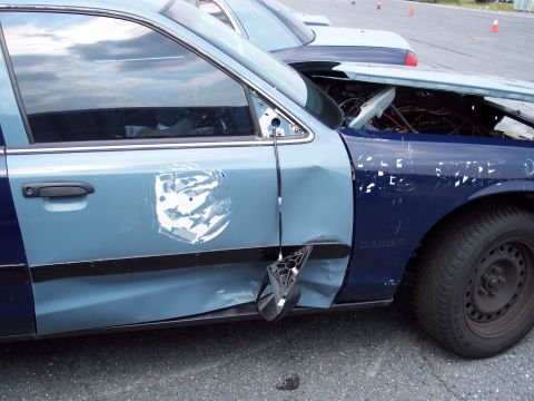 1991 Ford LTD Crown Victoria - A damaged 1991 Ford Crown Victoria is seen from the side, with its hood open and visible damage to the door and fender.
