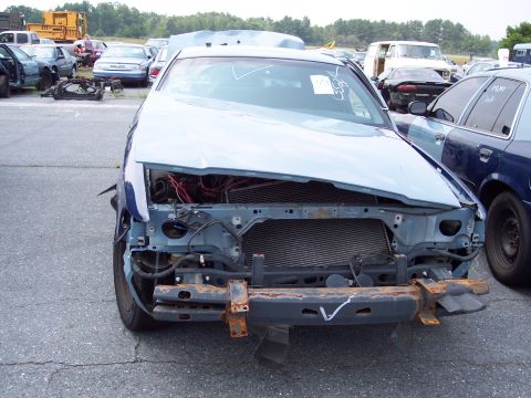 1991 Ford LTD Crown Victoria - A light blue 1991 Ford Crown Victoria LTD sits in a junkyard, its front end heavily damaged and grille missing.