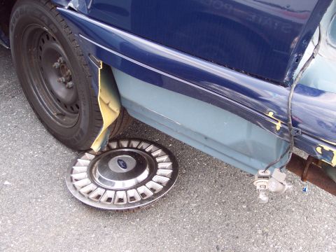 1991 Ford LTD Crown Victoria - A Ford hubcap is on the ground next to a damaged car fender, revealing the inner fender liner.