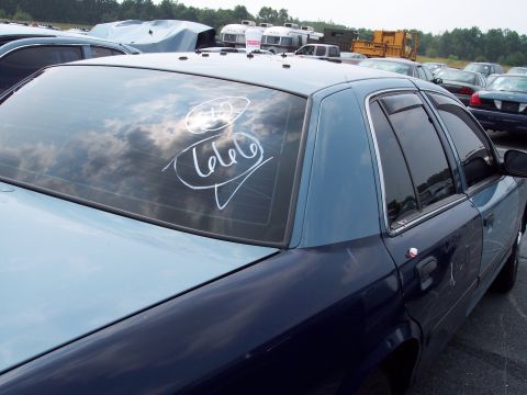 1991 Ford LTD Crown Victoria - A two-tone Ford Crown Victoria sedan is parked in an outdoor lot with other vehicles and trailers.