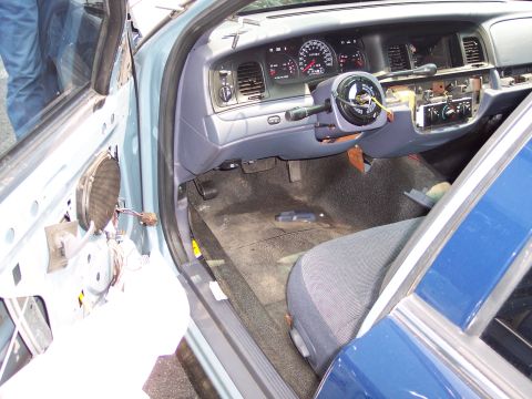 1991 Ford LTD Crown Victoria - The interior of a car is shown with parts removed, including the steering wheel and door panel, revealing the dashboard and wiring.