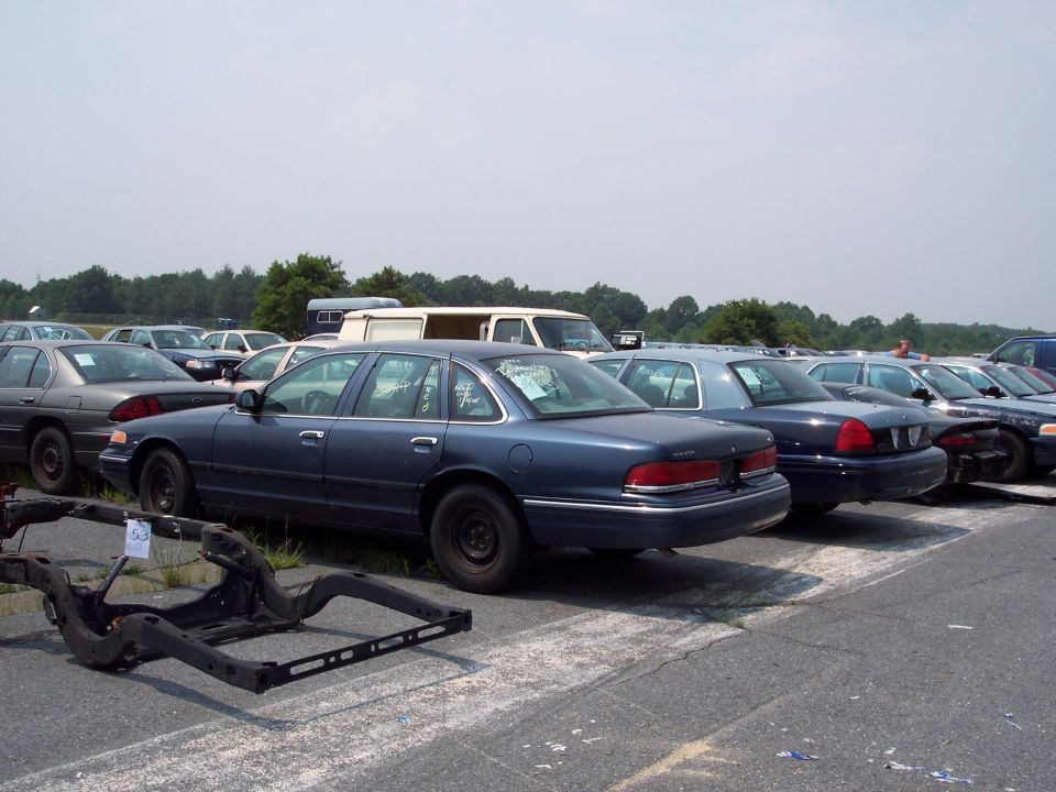 Row of Ford Crown Victoria sedans parked in a lot, one in foreground