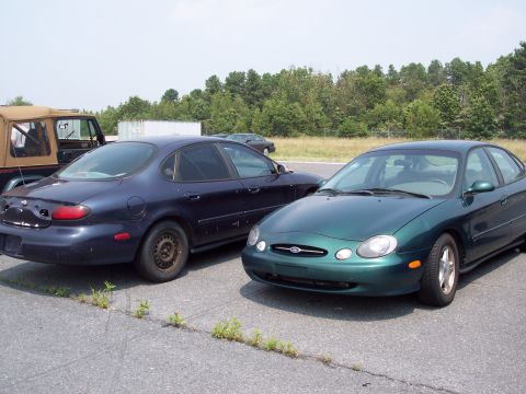 1991 Ford LTD Crown Victoria - Green Ford Taurus parked next to a dark blue sedan.
