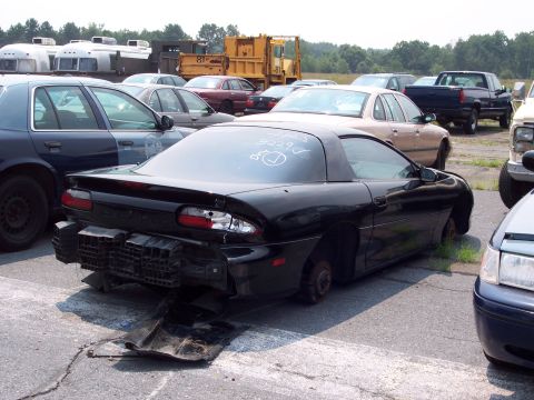 1991 Ford LTD Crown Victoria - Junkyard scene with a damaged black sports car and other vehicles visible.