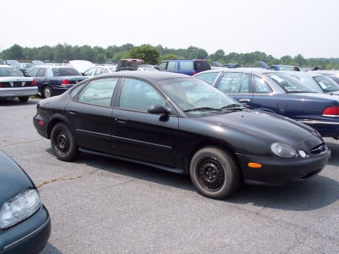 1991 Ford LTD Crown Victoria - A black sedan is parked in a lot with other vehicles.