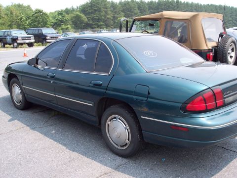 1991 Ford LTD Crown Victoria - A green sedan is parked in a lot with other vehicles visible in the background.