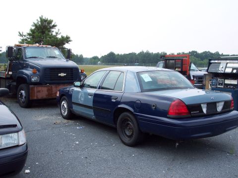 1991 Ford LTD Crown Victoria - A police car and a tow truck are parked in an outdoor lot.