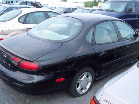 1991 Ford LTD Crown Victoria - A black sedan is parked in a lot with other vehicles visible in the background.