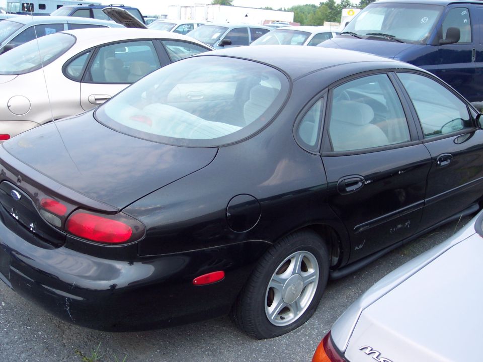 Black sedan rear view, parked in lot with other vehicles
