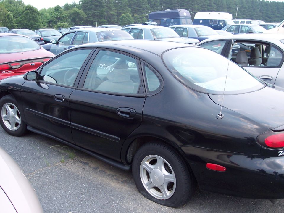 Black sedan with a flat tire parked in a lot with other cars