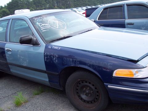 1991 Ford LTD Crown Victoria - A two-tone blue police car is parked in a lot with other vehicles, showing '16 TIRES' and 'STATE POLICE' markings.