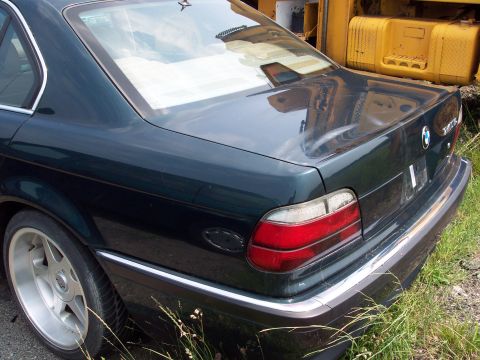 1991 Ford LTD Crown Victoria - A dark sedan is parked next to yellow construction equipment. The vehicle's rear is visible.