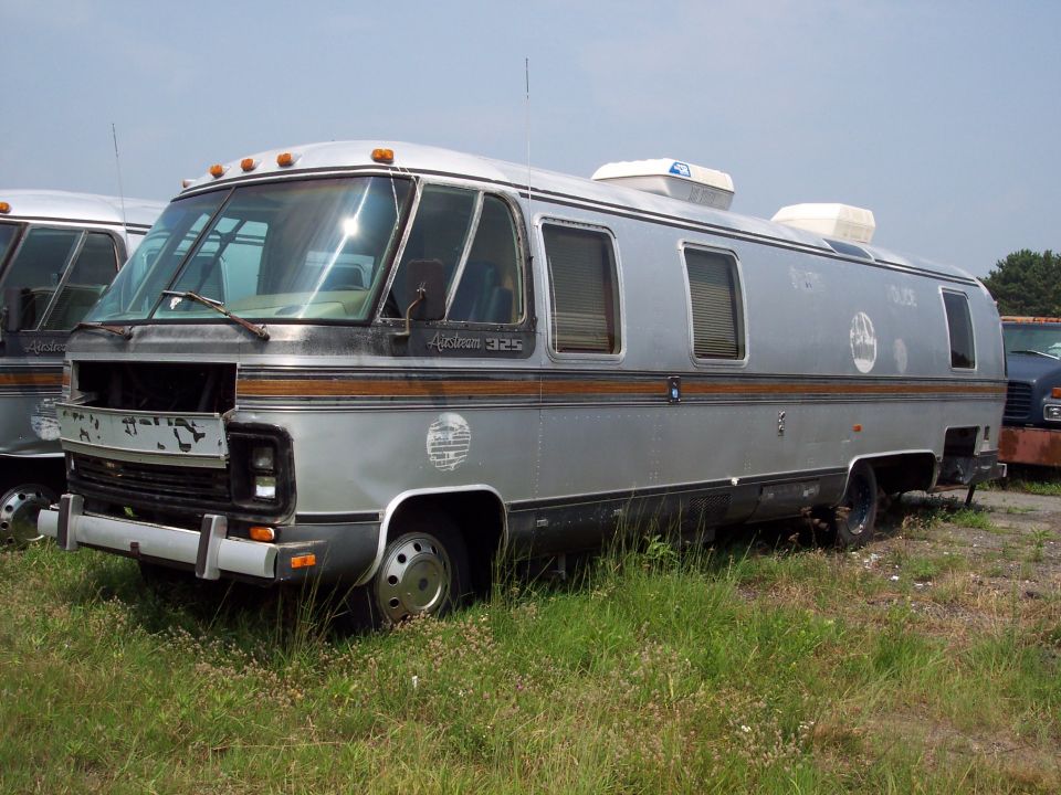 Silver Airstream 325 motorhome, front missing grille, parked in grass